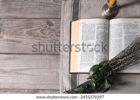 Bible, willow branches and church candle on wooden table, flat lay. Space for text