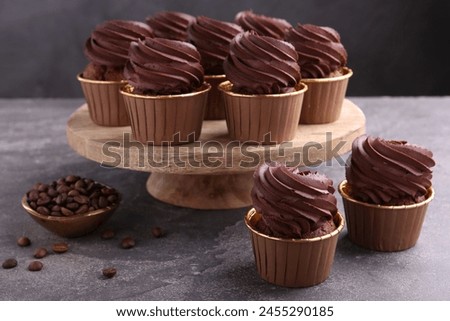 Delicious chocolate cupcakes and coffee beans on grey textured table