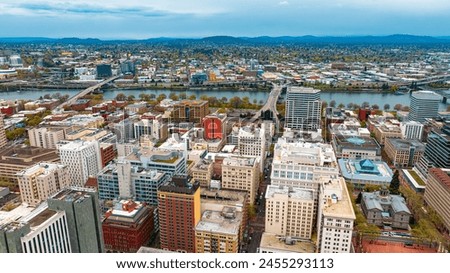 Downtown of Portland, Oregon, the USA with high-rise architecture. Twilight view of the city with mountain silhouettes at backdrop.