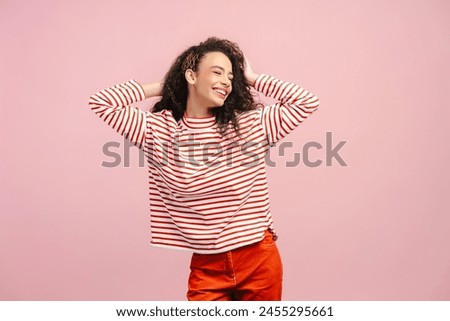 Excited girl, teenager wearing trendy shirt dancing with closed eyes isolated on pink background. Smiling stylish fashion model having fun posing for picture in studio