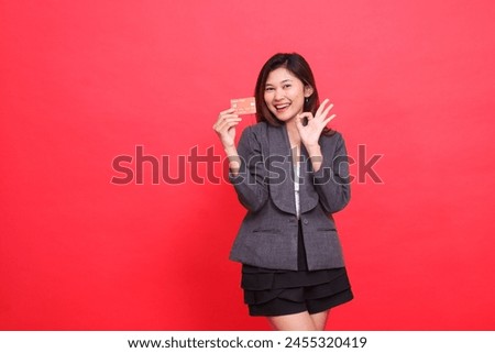 indonesia businesswoman expression happy OK sign ready and holding debit credit card wearing jacket and skirt red background. for financial, business and advertising concepts