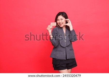 Asian businesswoman expression happy sign of love and holding debit credit card wearing jacket and skirt on red background. for financial, business and advertising concepts