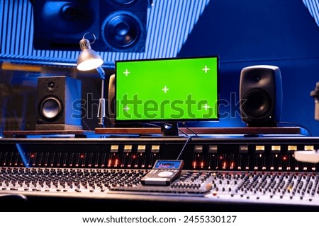 Empty control room with greenscreen on monitor and panel board, professional studio used for recording and editing tracks. Audio console helping with mixing and mastering music.