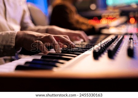 Singer songwriter creating new tracks on midi controller in studio, working with sound designer to record a song with electronic keyboard piano. Professional artist playing synthesizer. Close up.
