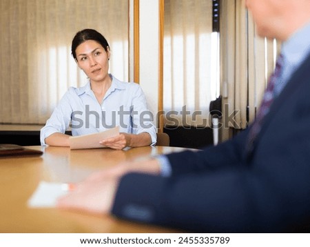 Two experienced business man and woman in office interior filling up documents