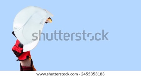 Hardhat in hands of man. White helmet for builder. Industrialist protective headgear. Hardhat on blue background. Clothes for construction workers. Hardhat made of white plastic. Industrial helmet Royalty-Free Stock Photo #2455353183