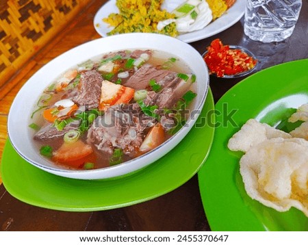 Serve beef rib soup on the table with sliced ​​fresh tomatoes and green onions. A typical Indonesian beef soup dish