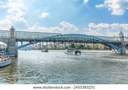 View of the Moscow river embakment, Pushkinsky bridge and cruise ships at sunset. Wide Moskva River, Pushkinsky bridge, Groky Park, Frunzenskaya embankment, Royalty-Free Stock Photo #2455383251