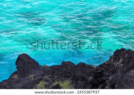 Dark cliffs and waves on the turqouise ocean. View on the romantic dangerous rocky shoreline, travel picture. Coastline with ocean surface. Sea and black volcanic rocks.