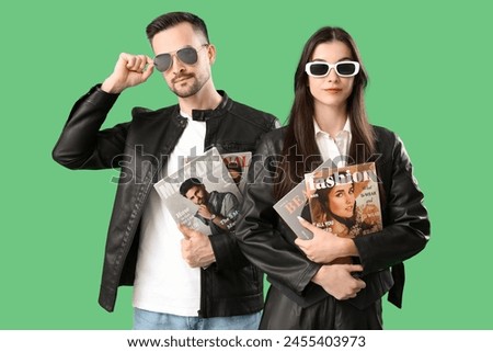 Cool young couple with magazines on green background