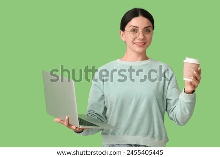 Female programmer with laptop and cup of coffee on green background