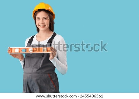 Young pregnant architect with level on blue background