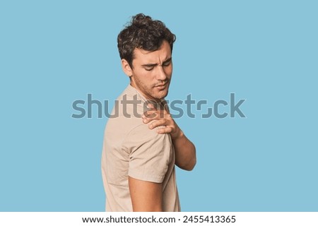 Young Hispanic man in studio having a shoulder pain.