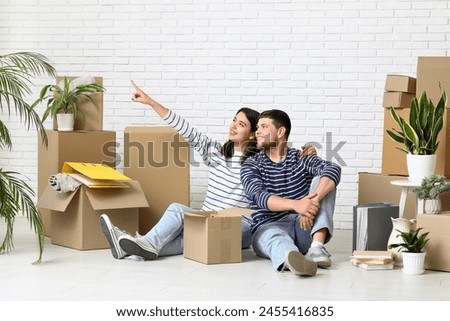Young woman pointing at something near her husband and belongings in their new house