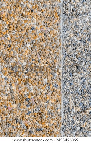 This is photo of building wall decorated by small grey and yellow stones. It's the close up view of colorful stones. It is view of texture of wall