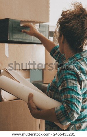 One alone woman working at home with cardboard carton box after relocating new home. Indoor leisure activity at home. Mortgage new beginnings adventure. Independence lifestyle lady. Moving apartment Royalty-Free Stock Photo #2455435281