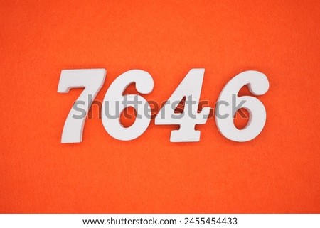 The number 7646 is made from white painted wood placed on a background of orange paper.