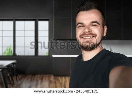 One man 30s adult caucasian male standing at home with a dark hair, bearded and a mustache looking at the camera. Happy smile confident real people
