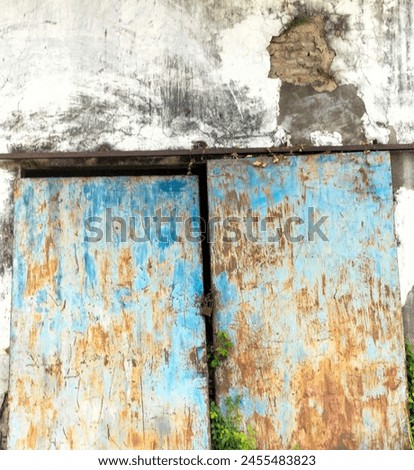 Rusty rustic metal door with blue and yellow paint. Selective focus.