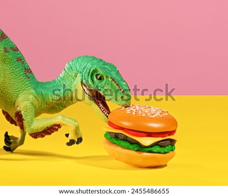 Green dinosaur bites a burger on pink and yellow background.
