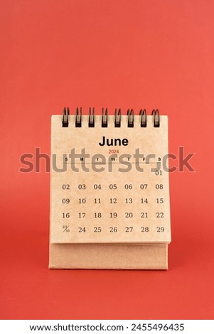June 2024 white mini desk calendar on red color background.