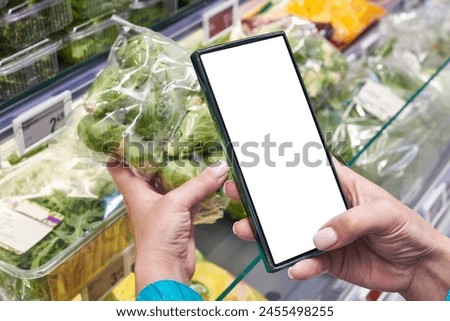 Brussels sprout vegetable in hand and smartphone in store isolated white