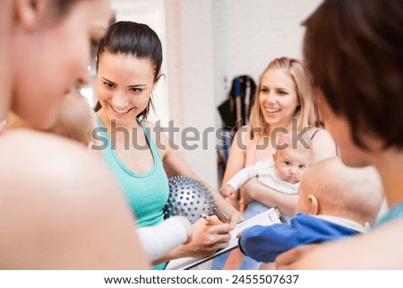 Group exercise class, mother working out with baby in gym. Moms staying active while boding with babies. New mom friends. Royalty-Free Stock Photo #2455507637