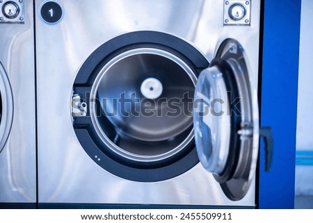 Qualified coin operated laundry machine in the public room to wash  cloths. Concept of a self service commercial laundry and drying machine in a public room. Coin operated Laundry Machines. Royalty-Free Stock Photo #2455509911