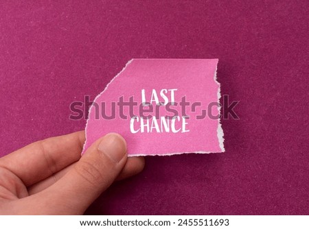 Last chance words written on ripped pink paper piece with purple background. Conceptual last chance symbol. Copy space.