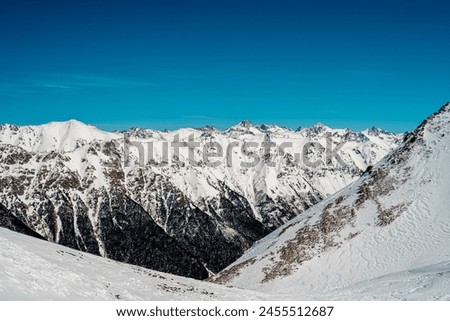 scenic natural picture with snow-capped huge mountain peaks and mountains, autumn bare trees, sky blue sky, snow lies on the mountain tops