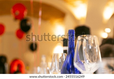 Detail of blue bottle, glasses on indoor background. Concept of feast or free time