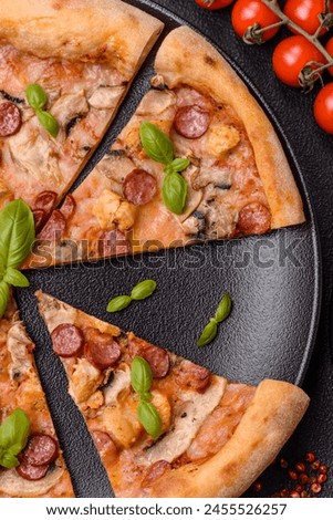 Delicious pizza with sausage, cheese, tomatoes, salt, spices and herbs on a dark concrete background