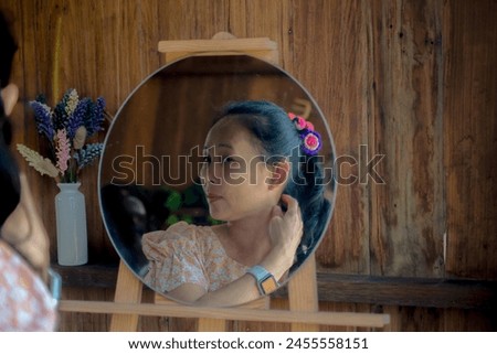 Asian woman looking in round mirror