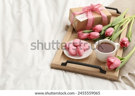 Tasty breakfast served in bed. Delicious macarons, tea, flowers, gift box and card with phrase I Love You on tray, space for text