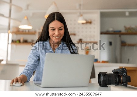 Woman working on laptop in home. Freelance photographer edit photos on computer.