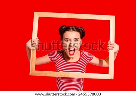 Portrait of her she nice cute charming attractive glamorous aggressive girl in striped t-shirt holding in hands wooden frame trying to break rules borders life lifestyle isolated over pink background Royalty-Free Stock Photo #2455598003