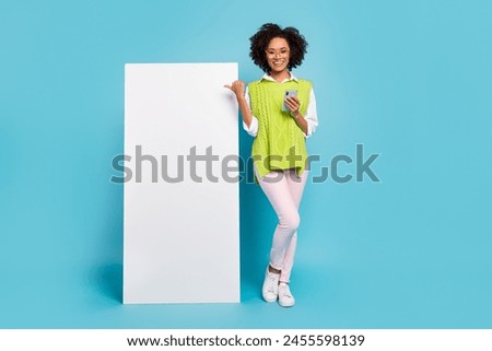 Full size photo of cool millennial brunette lady with telephone index promo wear spectacles vest pants sneakers isolated on blue background