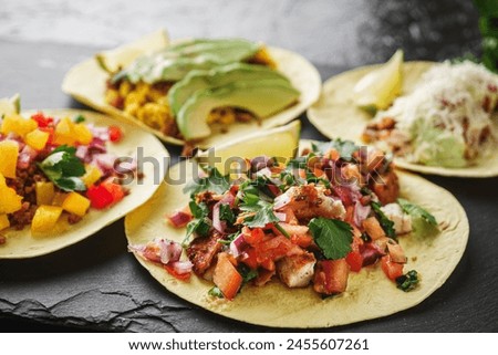 set of delicious fresh colorful tacos on a dark background.