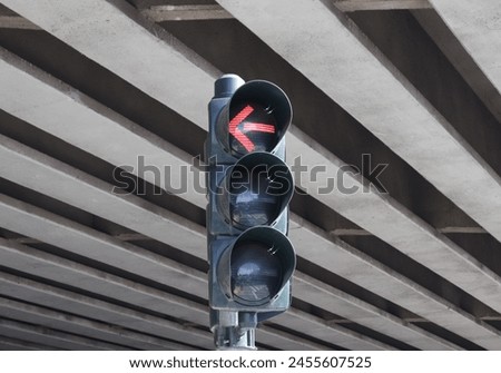 Red traffic light with arrow under the highway