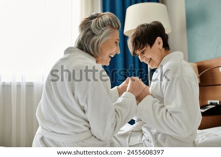 Two senior lesbian women sharing a tender moment in a bedroom. Royalty-Free Stock Photo #2455608397