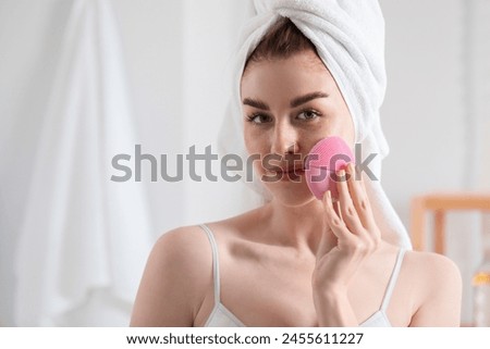 Washing face. Young woman with cleansing brush indoors, space for text