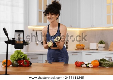 Smiling food blogger explaining something while recording video in kitchen Royalty-Free Stock Photo #2455611245
