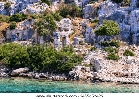 Time-worn Lycian ruins stand among wild shrubs on Kekova Island, vibrant colors. Famous boat tour from Demre, Antalya, Turkiye (Turkey) Royalty-Free Stock Photo #2455652499