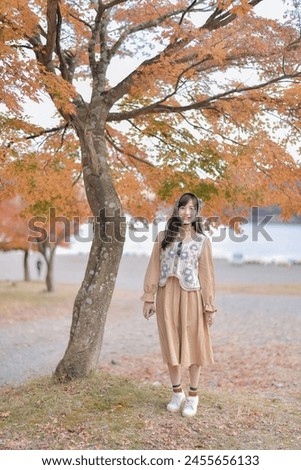 Asian woman in Japan's fall beauty, a cheerful holiday portrait in yellow and red foliage. A journey capturing essence of nature, fashion, and casual elegance.