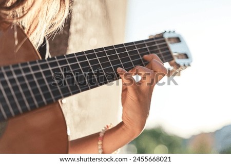 Close up of a female hand on the frets of a guitar with the blurred background Royalty-Free Stock Photo #2455668021
