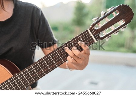 Close up of a female hand on the frets of a guitar with the blurred background Royalty-Free Stock Photo #2455668027