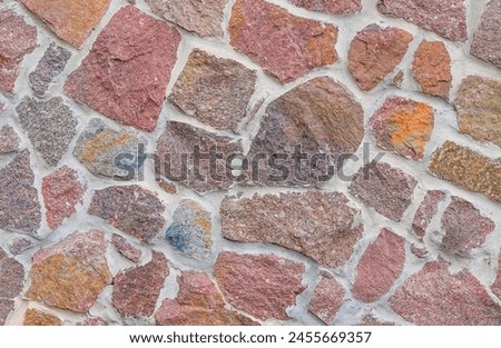 It's close up view of colorful wall. Its photo of the multicolor stonewall. It is photo of multicolored srone wall. its view of red sidewalk. It's view of mosaic stonewall