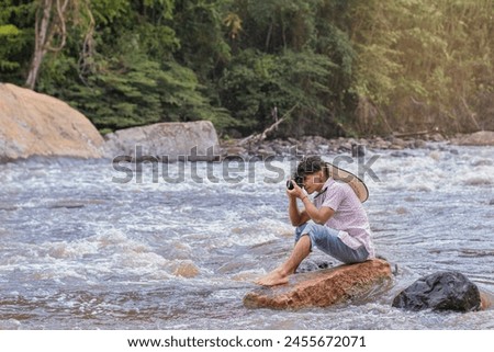 lifestyle. young latino man sitting on a rock taking pictures with an analog camera