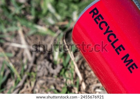 Recycling Reminder. The Saga of the Red Can. Recycle me, black letters. Symbols. Thrown away in the park. Save the nature, concept. Royalty-Free Stock Photo #2455676921