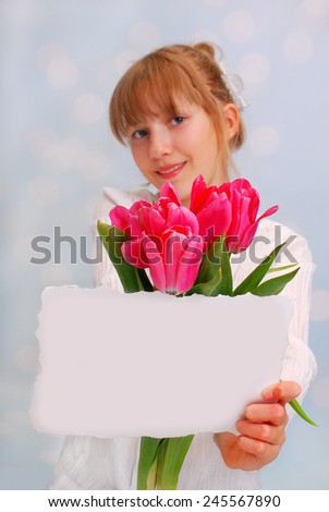 beautiful young girl giving bouquet of pink tulips and greeting card ( focus on flowers)